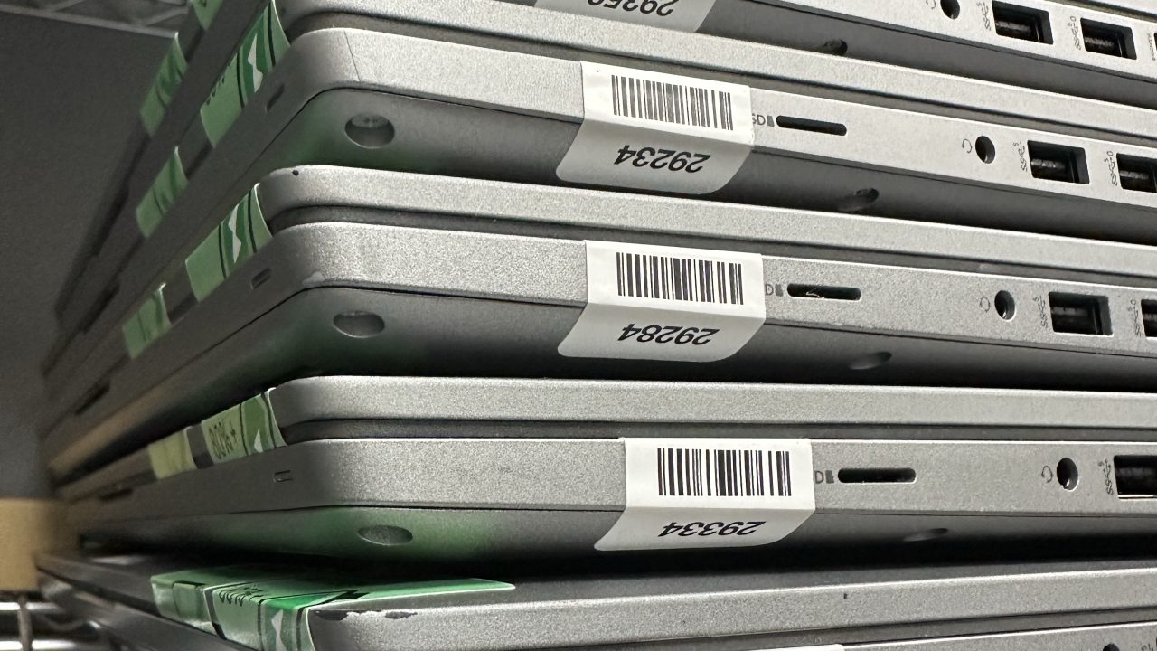 stack of closed gray laptops with a label visible on the side of the case
