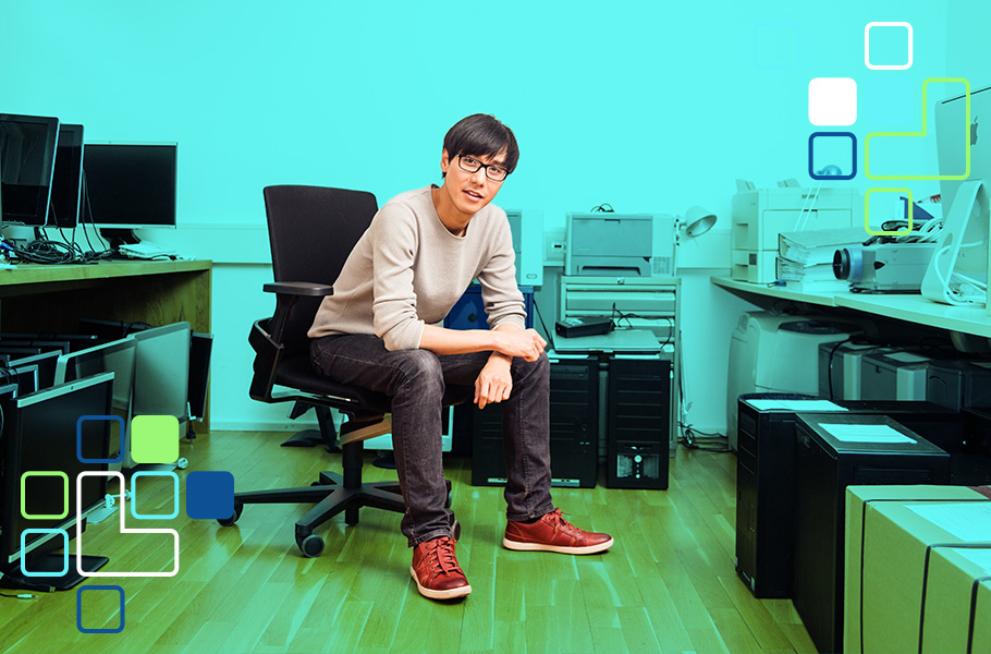An It guy sitting on a chair surrounded by old computer equipment
